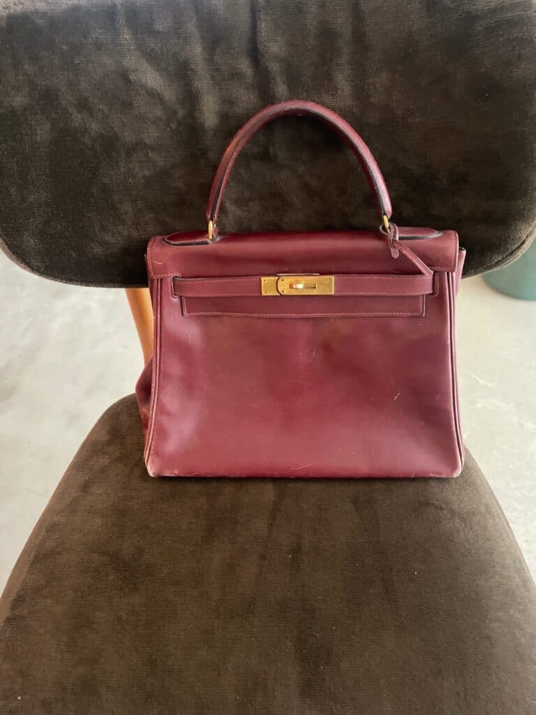 “Stima di una borsa vintage Hermes in pelle bordeaux con chiusura dorata che mostra segni di usura”