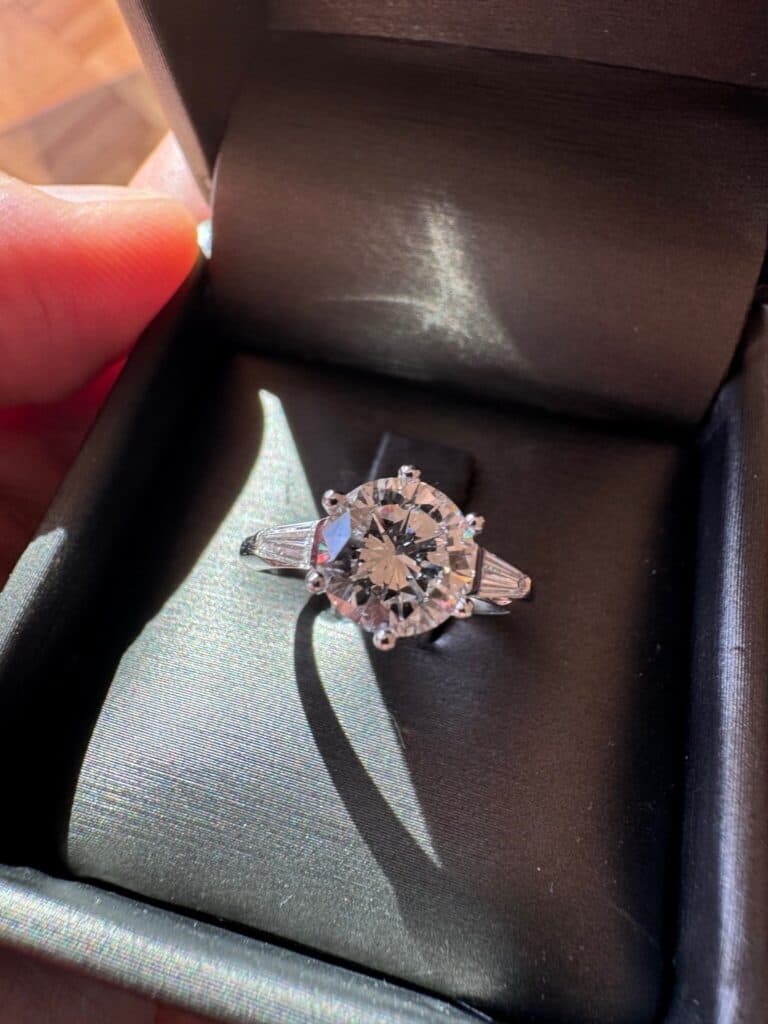 “Stima di un’elegante anello in oro grigio massiccio con diamante solitario da 1.79ct e accenti di diamanti trapezoidali”